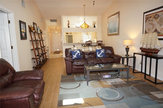 living room featuring lofted ceiling, a chandelier, and hardwood / wood-style flooring