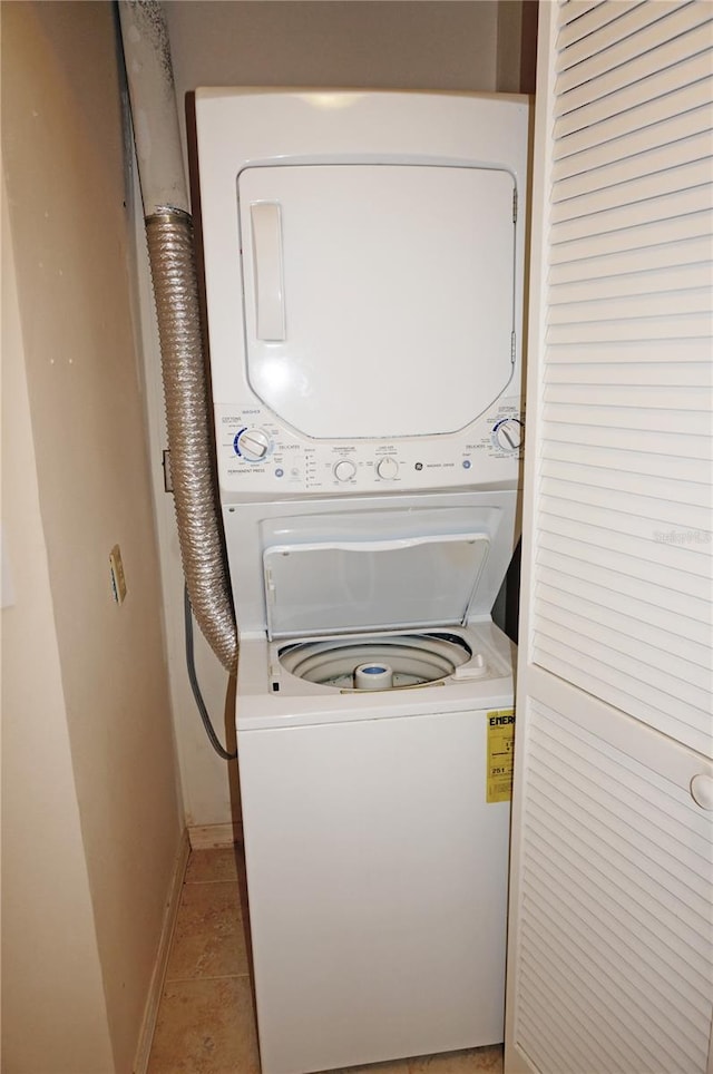 laundry area featuring stacked washer and dryer and light tile floors