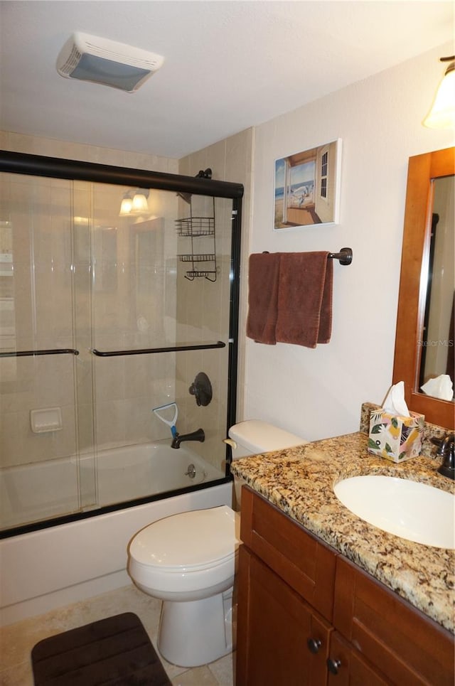 full bathroom featuring tile flooring, vanity, toilet, and bath / shower combo with glass door