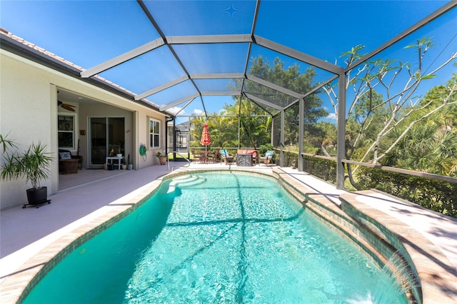 view of swimming pool with glass enclosure, ceiling fan, and a patio area