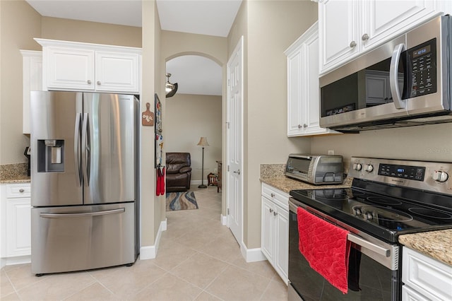 kitchen with stainless steel appliances, white cabinetry, and light stone counters