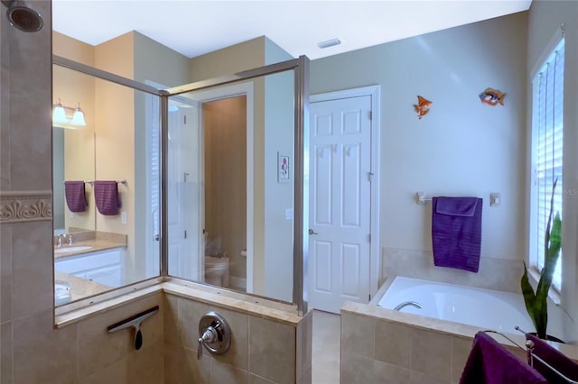 bathroom with sink, plenty of natural light, toilet, and tiled bath