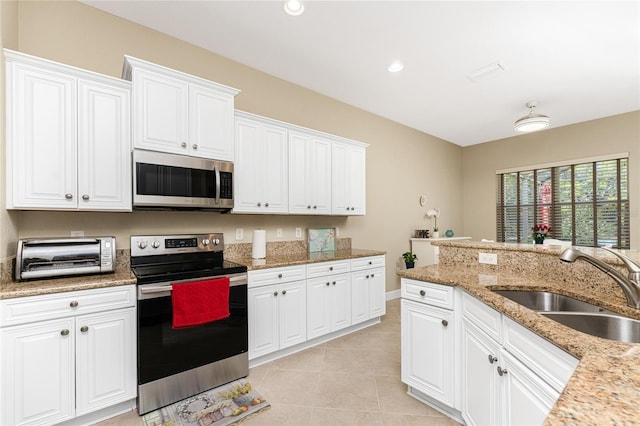 kitchen featuring white cabinets, stainless steel appliances, sink, light tile patterned flooring, and light stone counters