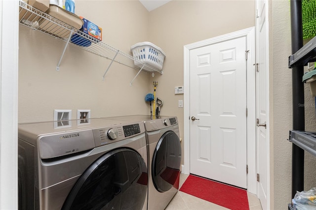 laundry area with washing machine and clothes dryer and light tile patterned floors