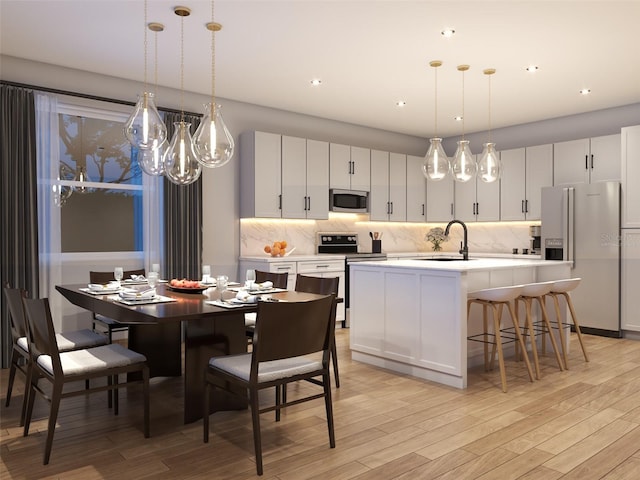 kitchen with backsplash, white cabinetry, decorative light fixtures, fridge with ice dispenser, and a center island with sink