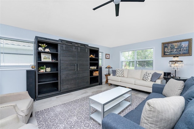 living room featuring a barn door, ceiling fan, and built in shelves