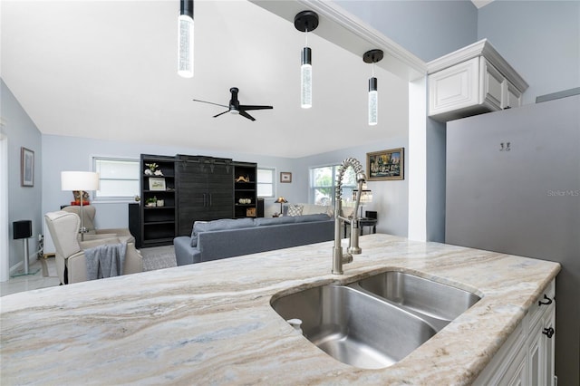 kitchen featuring light stone countertops, sink, refrigerator, decorative light fixtures, and white cabinets