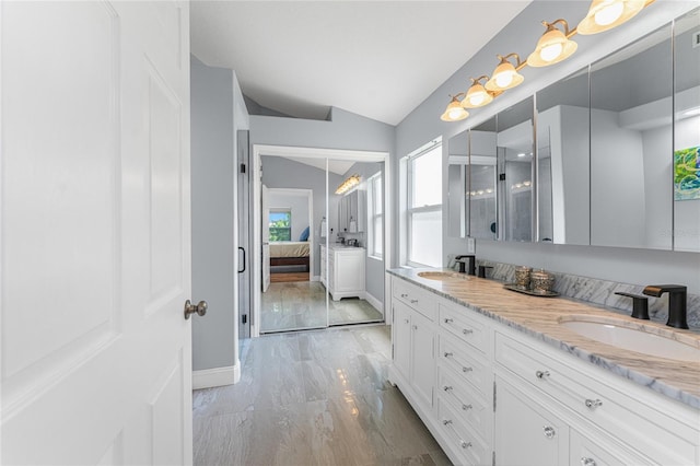 bathroom featuring vanity, wood-type flooring, and vaulted ceiling