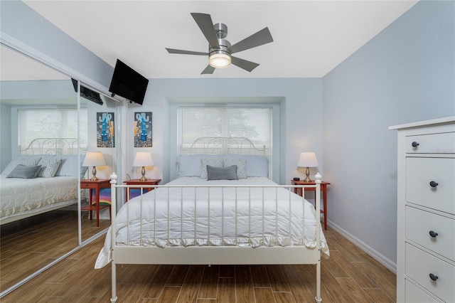 bedroom with ceiling fan, wood-type flooring, and multiple windows