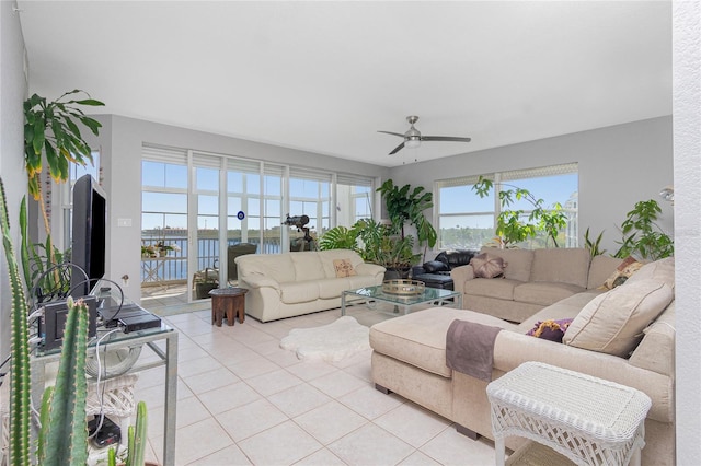 tiled living room with a wealth of natural light, ceiling fan, and a water view