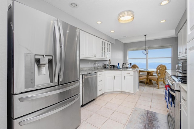 kitchen featuring stainless steel appliances, white cabinets, light tile floors, and hanging light fixtures