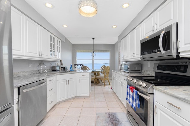 kitchen featuring light stone counters, light tile floors, white cabinets, hanging light fixtures, and stainless steel appliances