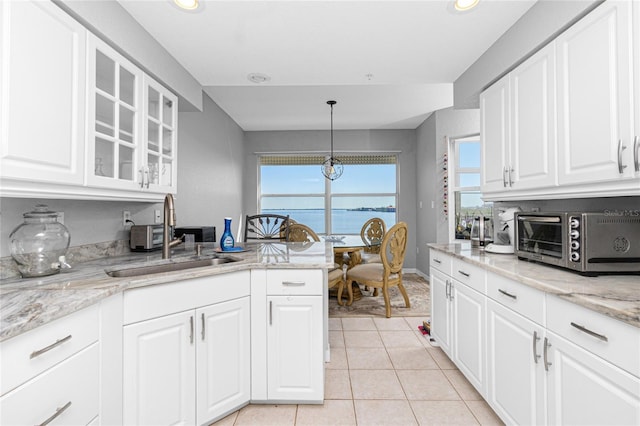 kitchen featuring decorative light fixtures, sink, light tile flooring, and white cabinetry