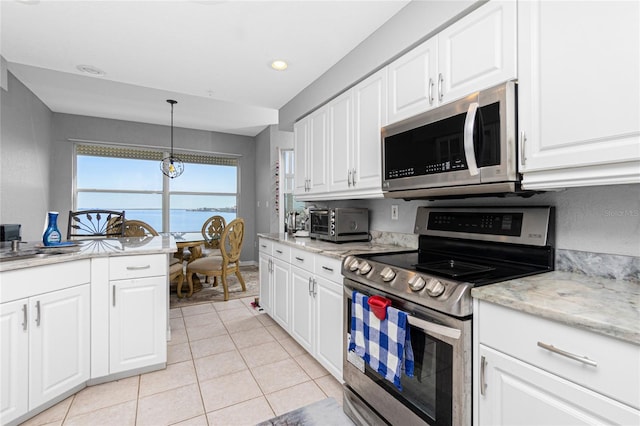 kitchen featuring appliances with stainless steel finishes, light tile floors, white cabinets, and hanging light fixtures