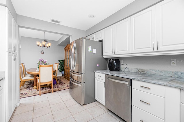 kitchen featuring pendant lighting, white cabinets, light tile flooring, appliances with stainless steel finishes, and light stone counters