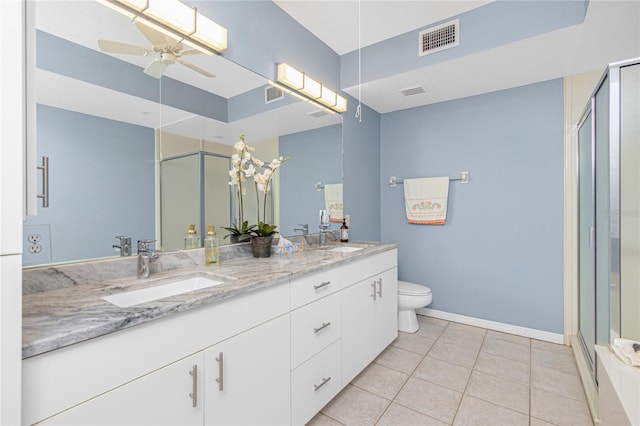 bathroom with vanity with extensive cabinet space, tile floors, dual sinks, toilet, and ceiling fan