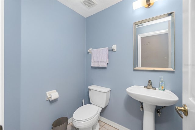 bathroom with toilet, tile floors, and sink