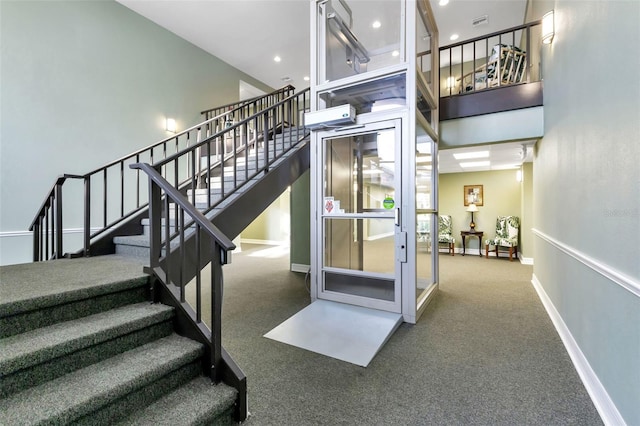 stairway featuring a towering ceiling and carpet floors