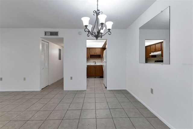 unfurnished dining area with light tile patterned floors, an inviting chandelier, and sink