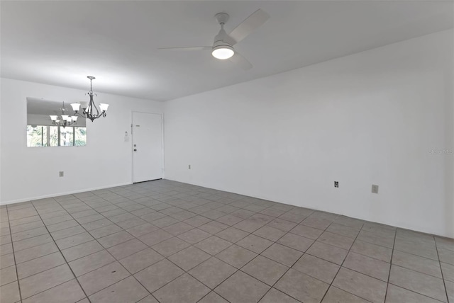 tiled spare room featuring ceiling fan with notable chandelier