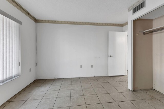 unfurnished bedroom featuring a textured ceiling, light tile patterned flooring, and a closet