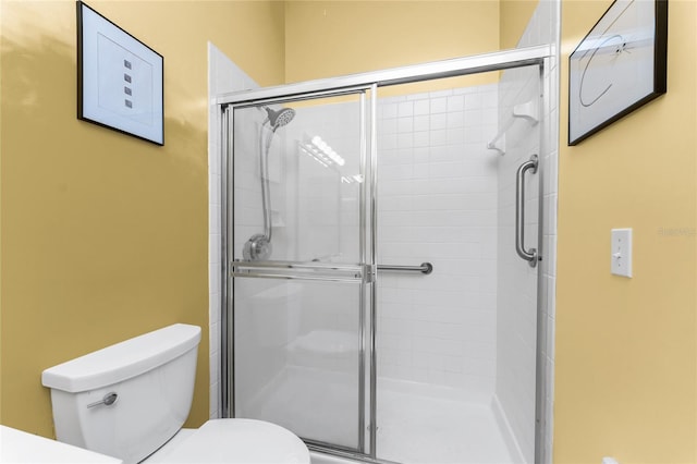 bathroom featuring toilet and a shower with door