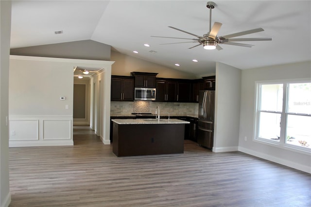 kitchen with vaulted ceiling, an island with sink, stainless steel appliances, and wood-type flooring