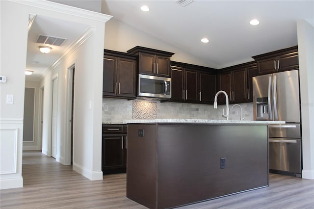 kitchen featuring dark brown cabinetry, light hardwood / wood-style floors, tasteful backsplash, and stainless steel appliances