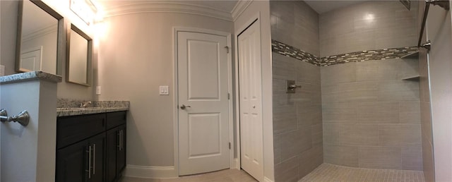 bathroom with ornamental molding, tiled shower, and vanity with extensive cabinet space