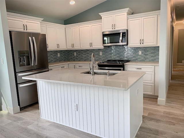 kitchen featuring appliances with stainless steel finishes, a center island with sink, backsplash, and white cabinets