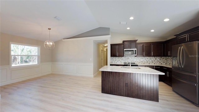 kitchen with light stone countertops, backsplash, light hardwood / wood-style flooring, stainless steel appliances, and lofted ceiling