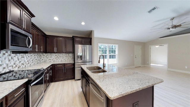 kitchen with light wood-type flooring, backsplash, appliances with stainless steel finishes, sink, and ceiling fan