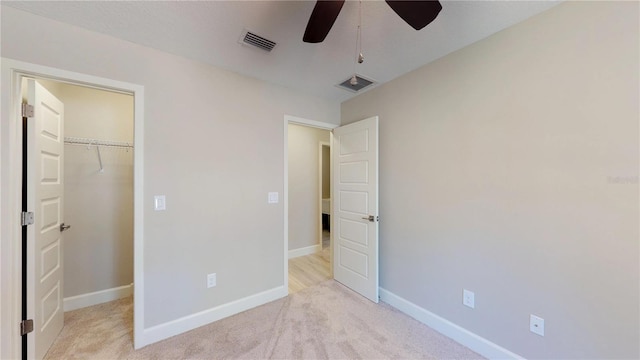 unfurnished bedroom with a spacious closet, a closet, light carpet, and ceiling fan