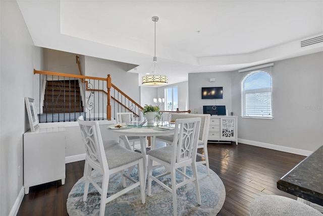 dining space with a raised ceiling and dark hardwood / wood-style flooring