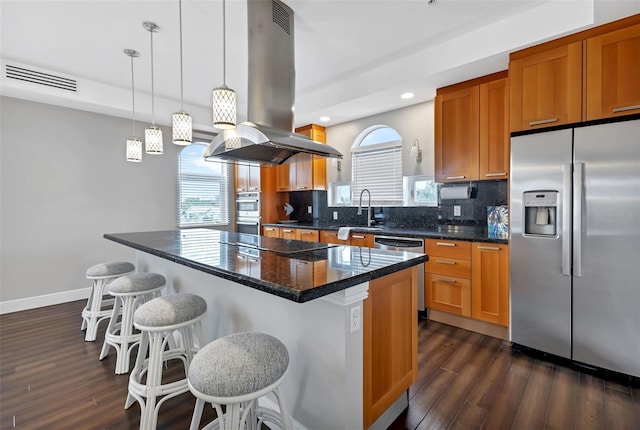 kitchen featuring dark wood-type flooring, a kitchen island, island range hood, stainless steel appliances, and backsplash