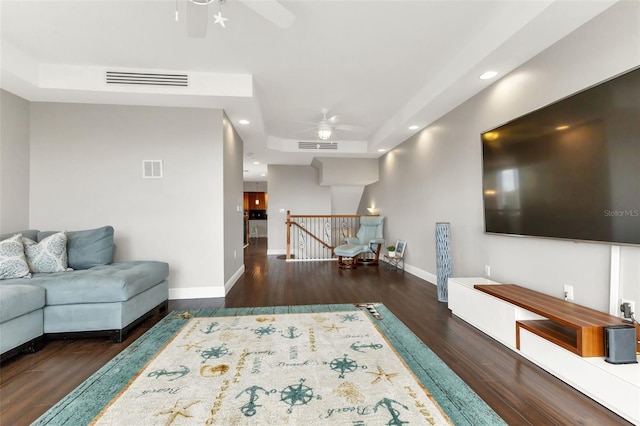 living room featuring a raised ceiling, ceiling fan, and dark hardwood / wood-style flooring