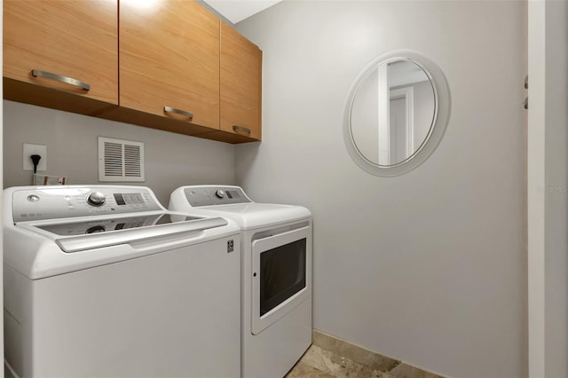 laundry room with cabinets, light tile floors, and separate washer and dryer