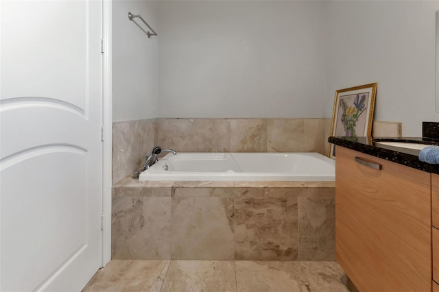 bathroom featuring a relaxing tiled bath, vanity, and tile floors