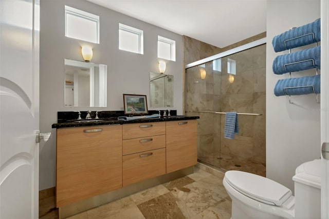 bathroom with a shower with shower door, double vanity, toilet, and tile floors