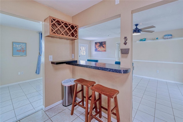 kitchen with a breakfast bar area, ceiling fan, kitchen peninsula, and light tile flooring