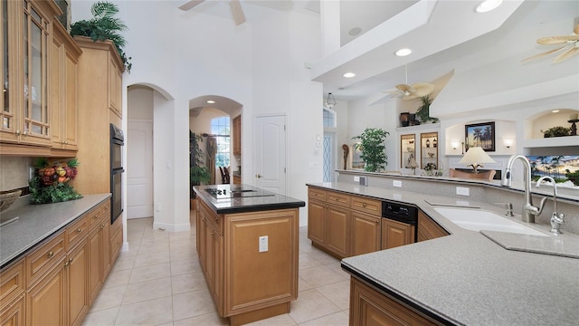 kitchen featuring a kitchen island, ceiling fan, black appliances, sink, and light tile floors