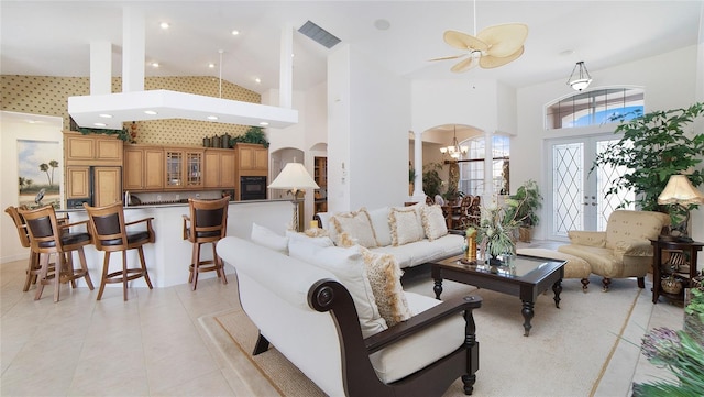 living room featuring high vaulted ceiling, light tile flooring, and ceiling fan with notable chandelier