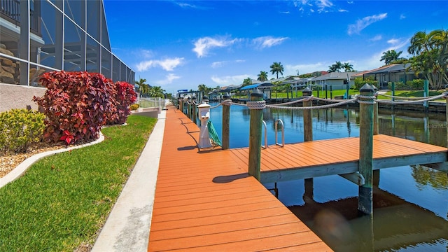 dock area with a lanai, a lawn, and a water view