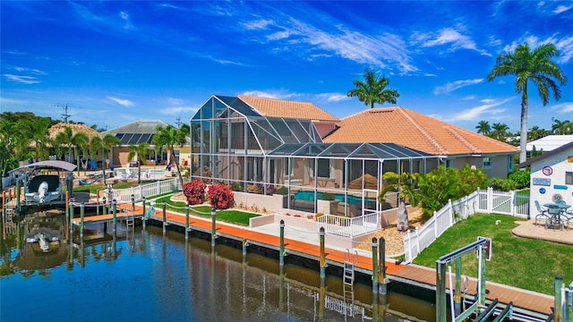 back of property featuring a water view, a yard, and a lanai