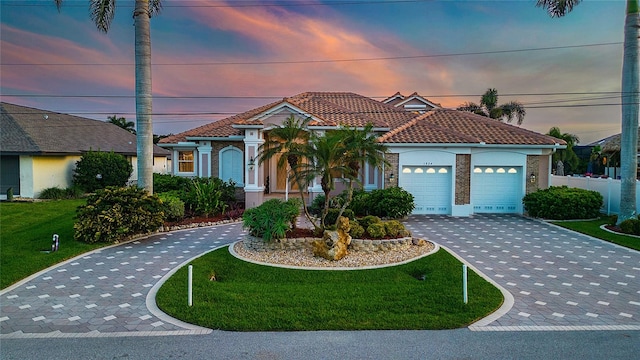 mediterranean / spanish-style home with a yard and a garage