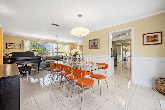 dining space featuring a textured ceiling, crown molding, and light tile floors