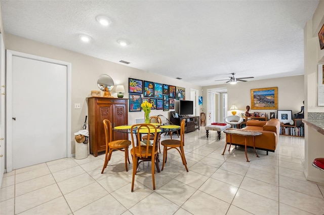 tiled dining room with ceiling fan and a textured ceiling