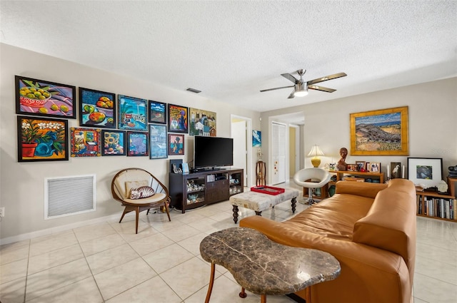 living room with ceiling fan, light tile flooring, and a textured ceiling