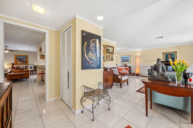 hall featuring ornamental molding, a textured ceiling, and light tile floors