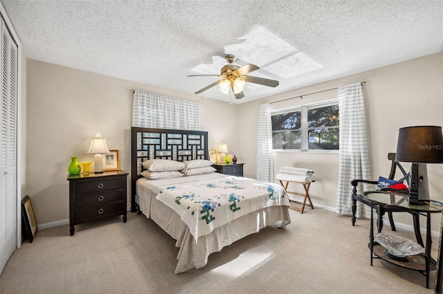 bedroom featuring a closet, light carpet, ceiling fan, and a textured ceiling